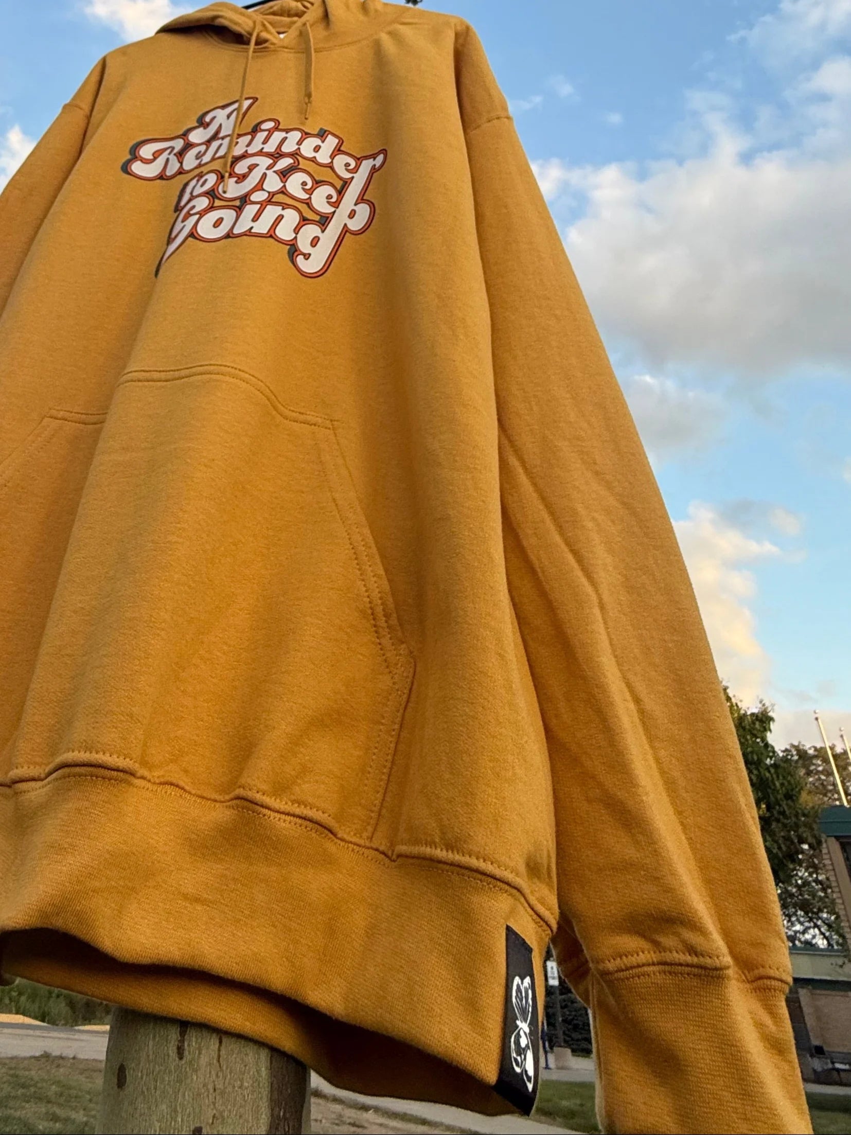 Yellow sweatshirt with text on a tree against a blue sky
