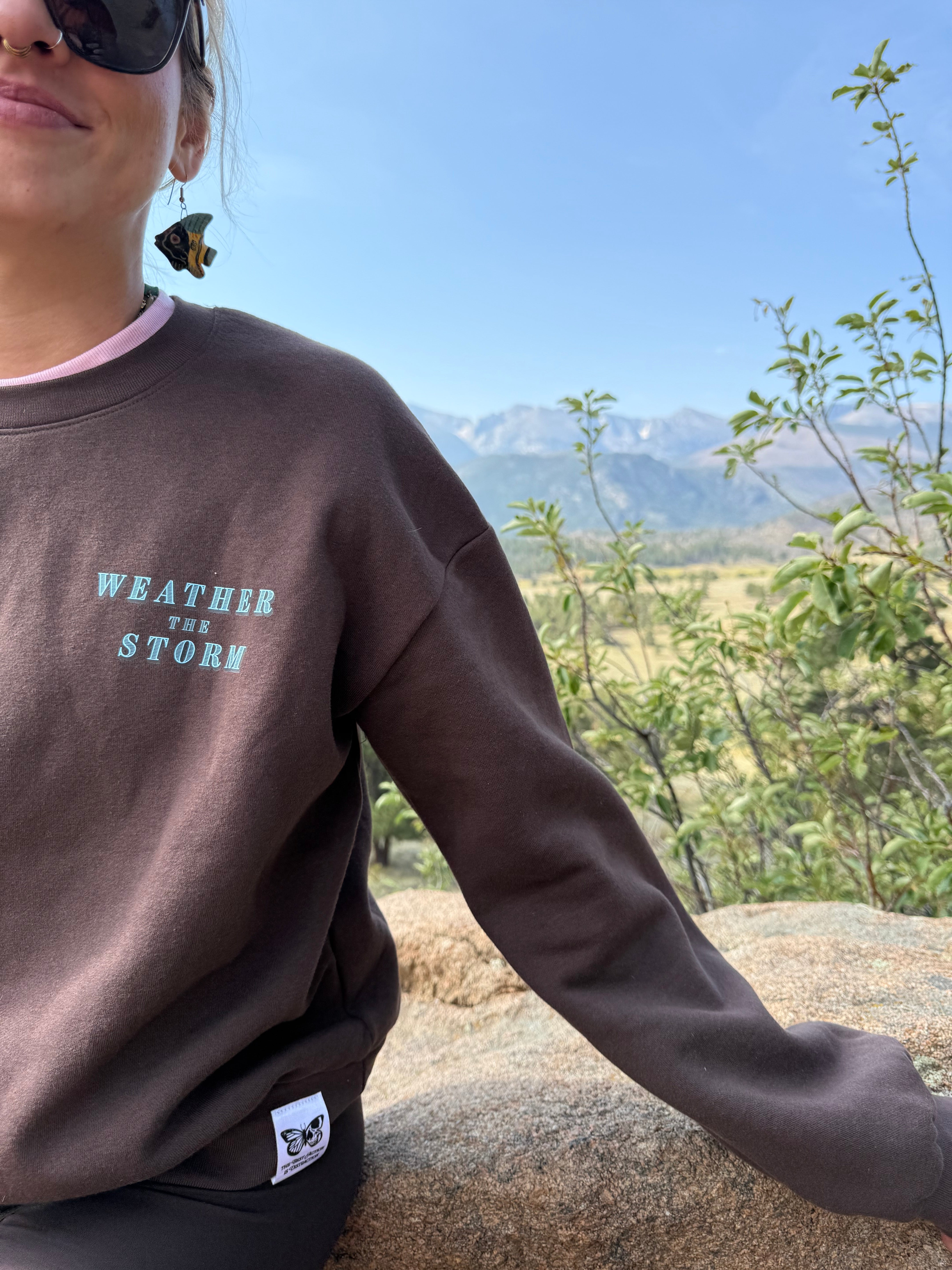 Person wearing a brown sweatshirt with text outdoors