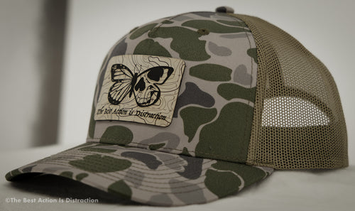Camouflage cap with a butterfly design and text on a neutral background